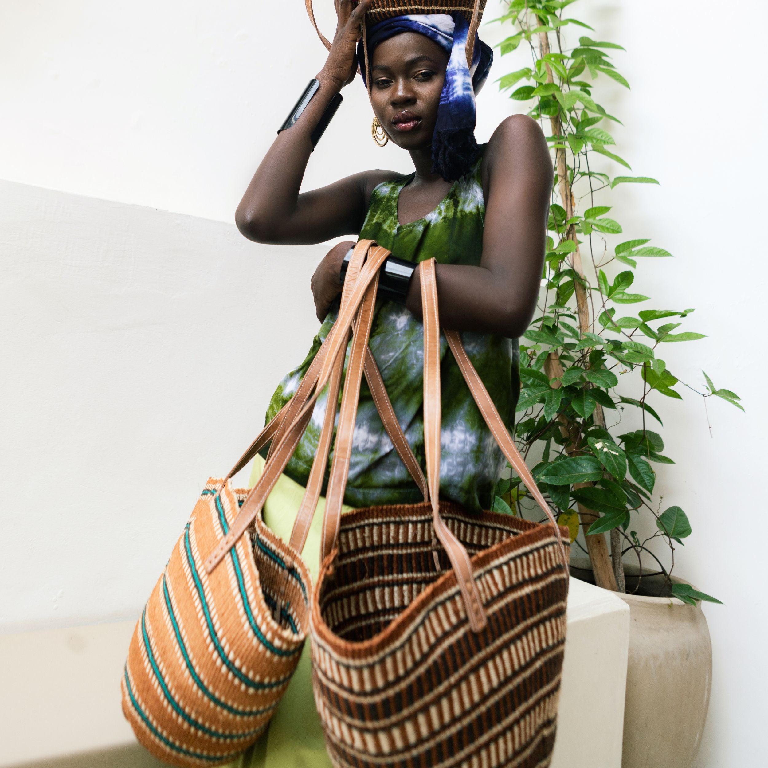 Editorial photo: Model is holding the Shopping Bag in Sisal Turquoise Stripes as well as the Shopping Bag in Sisal Brown. She is wearing the Sleeveless Top in Tie Dye Intense Green.
