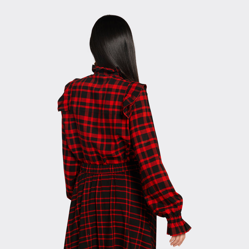 Black shirt with ruffles on the front in maasai fabric with red checks on model seen from the back