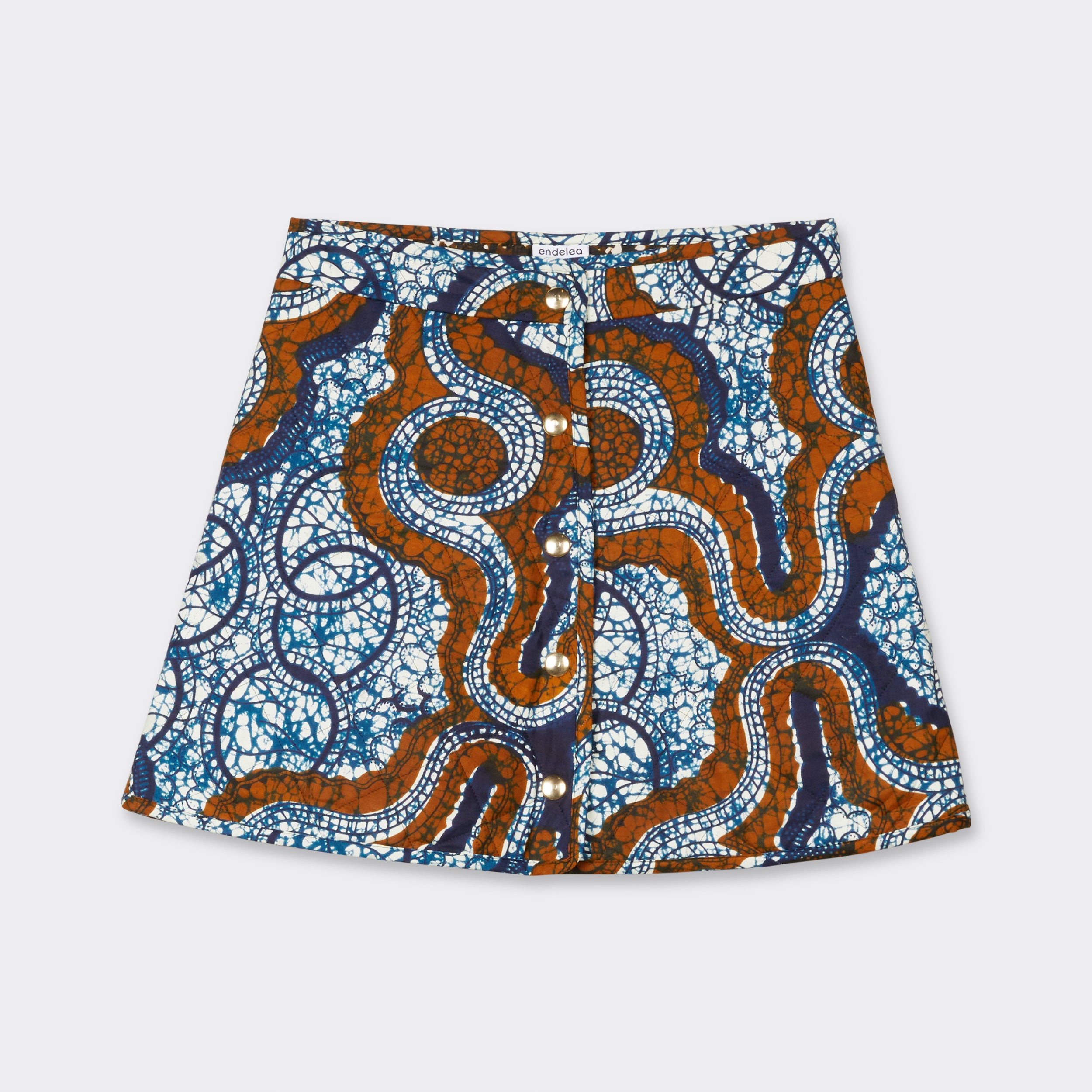 Reversible quilted mini skirt in African waxed fabric in blue& brown "marble" pattern with golden snap buttons on one model