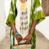 Editorial photo: Model wears the Kimono in Tie Dye Intense Green with a cream dress underneath and a  gold necklace. She is holding a Mini Shopping Bag in Sisal Turquoise. 