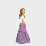 Model, who is a child, wears a Flounced Maxi Skirt Baby in Wax Pretty Little Flowers with colors pink and blue with a plain white tshirt