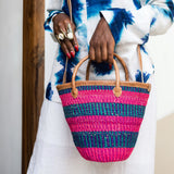 Editorial photo: Model holds the Mini Shopping Bag in Sisal Pink & Blue. She is wearing the Shirt in Tie Dye White and Blue with white pants.