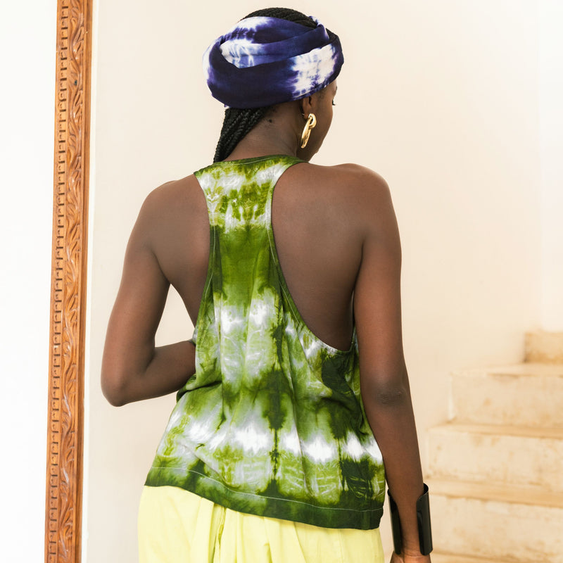 Editorial photo: Model wears a Sleeveless Top in Tie Dye Intense Green with a yellow skirt. She also wears a Pareo in Tie Dye Soft Blue on her head.