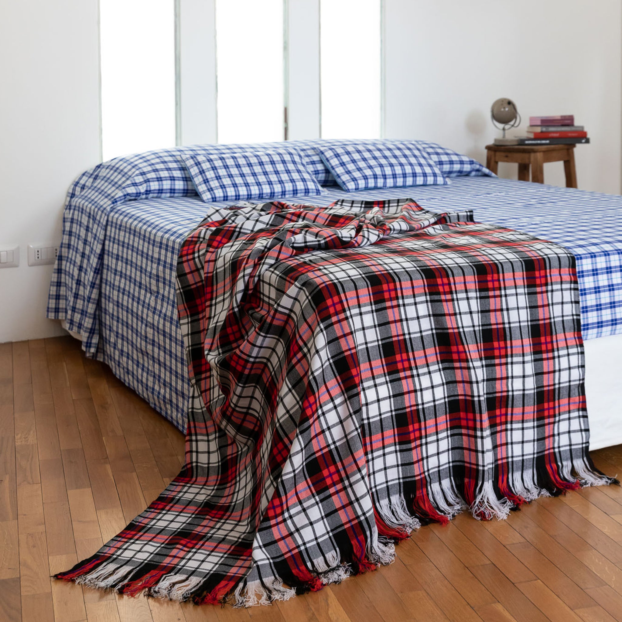 Checked blanket black, white and red in Maasai Shuka fabric above double bed