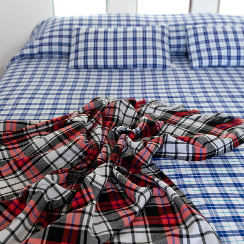 Checked blanket in black, white and red in Maasai Shuka fabric above double bed