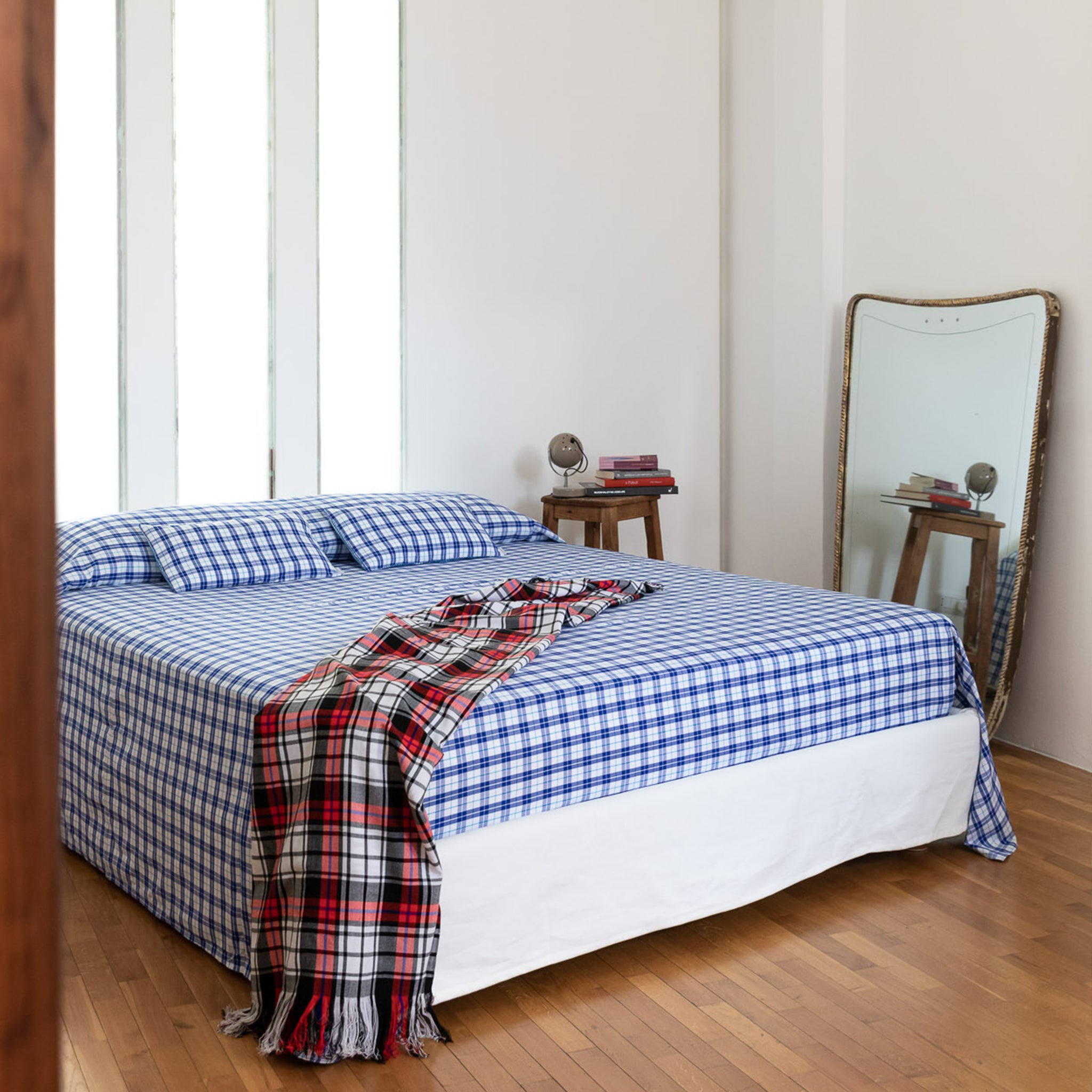 Double bed with Maasai checkered bedspread in blue&white and matching plaid