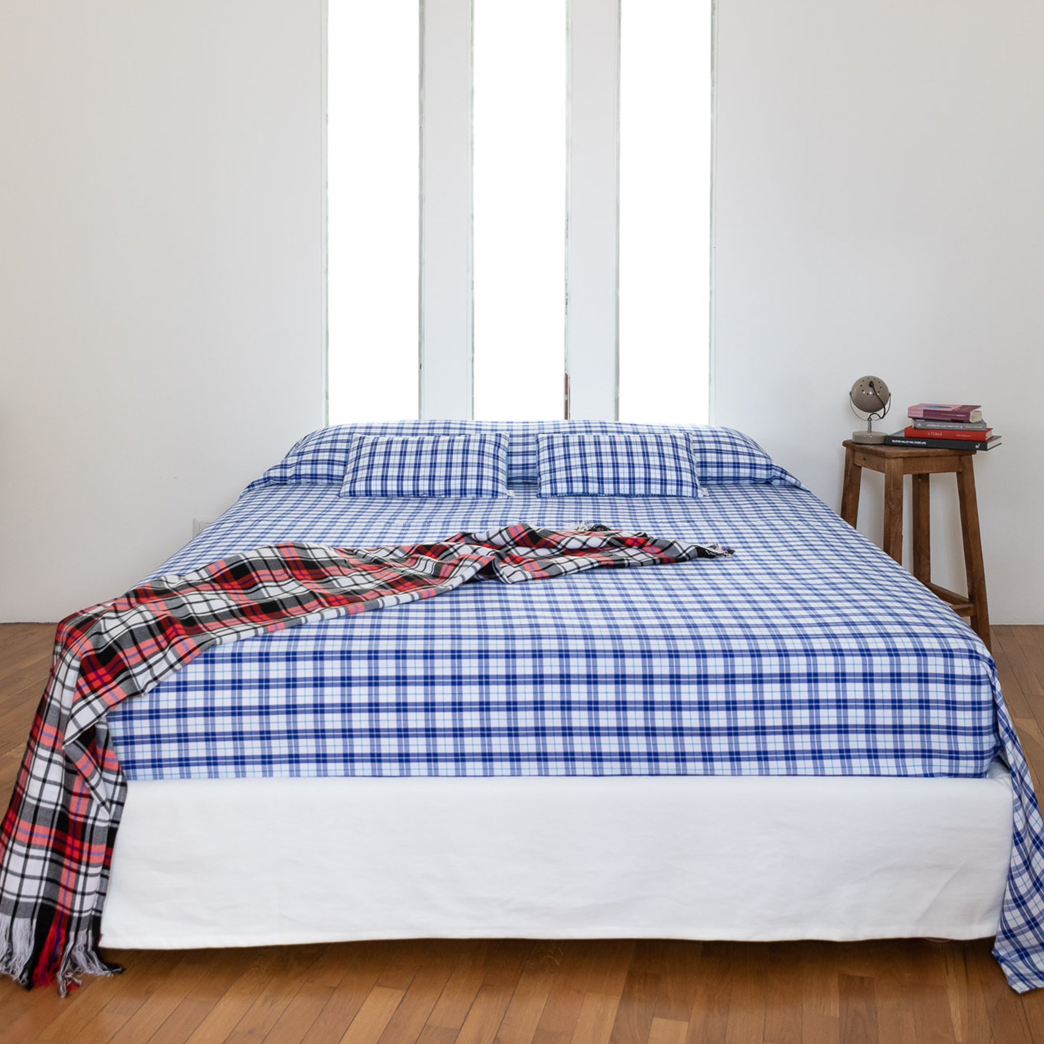 Double bed with Maasai checkered bedspread in blue&white and matching plaid