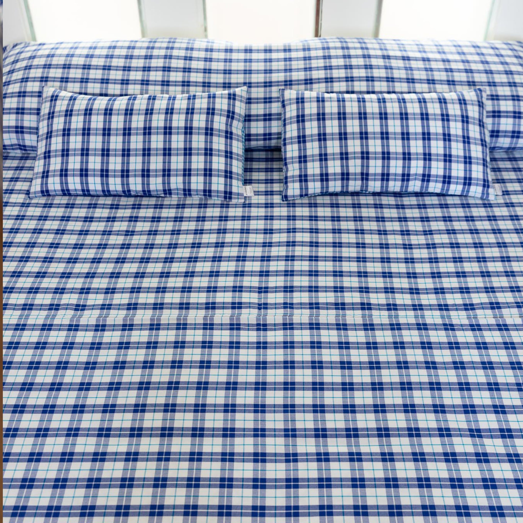 Double bed with Maasai checkered bedspread in blue&white and matching cushions
