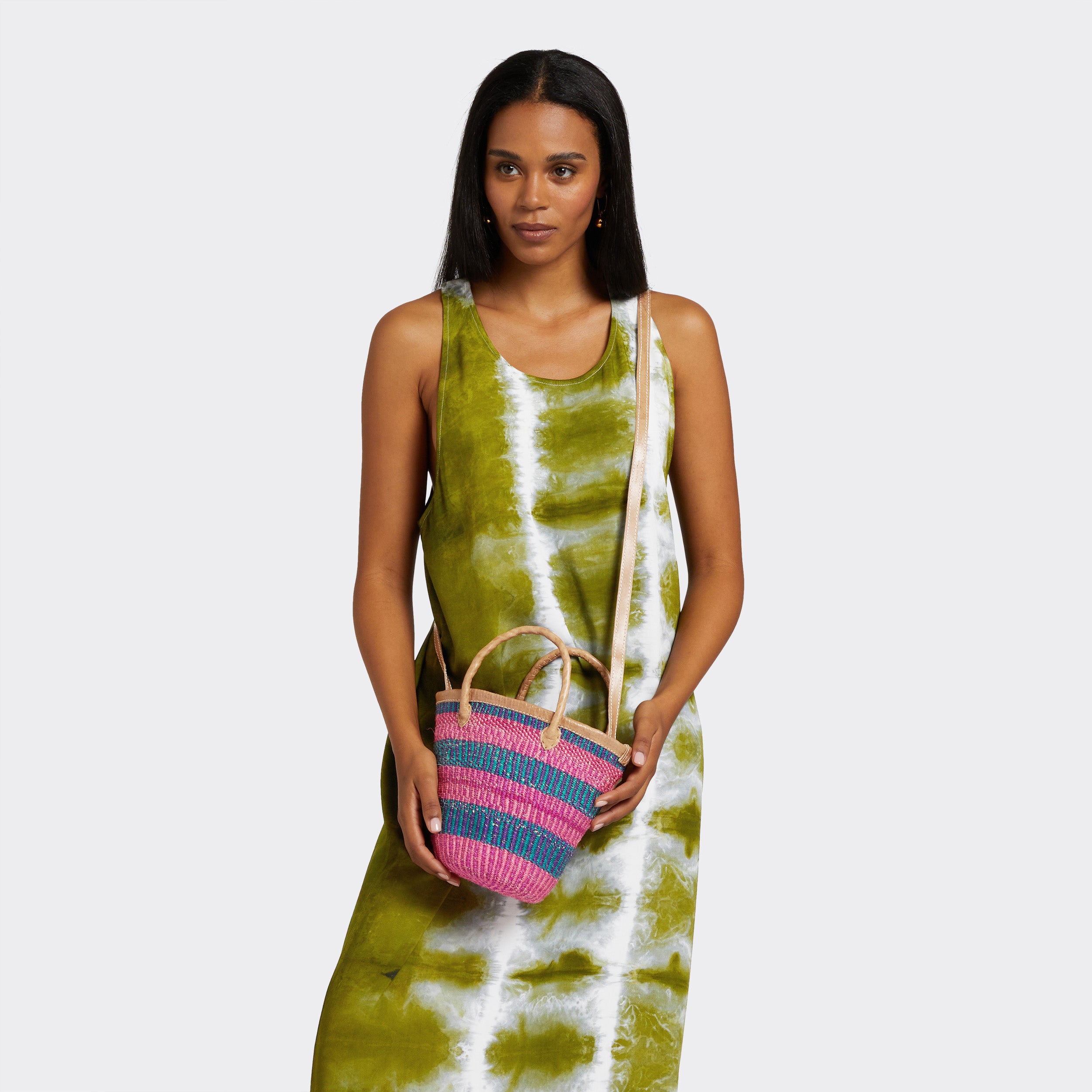 Model is holding the Mini Shopping Bag in Sisal Pink & Blue with the colors pink and blue. She is wearing a Tie Dye Long Dress in Intense Green which has the colors green and white.