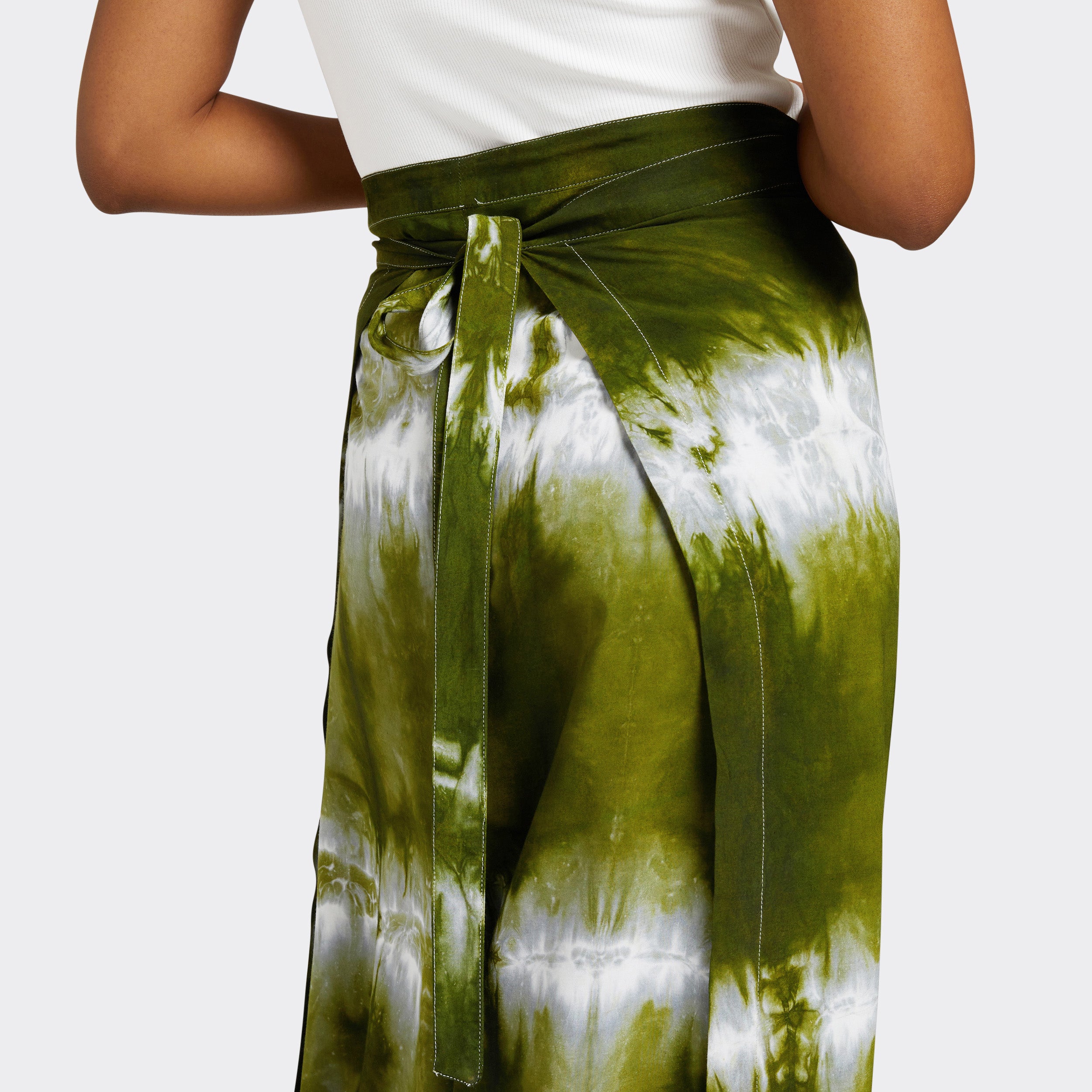 Model wears Wrap Trousers in Tie Dye Intense Green where you can she the tie knot detail, with a plain white top.