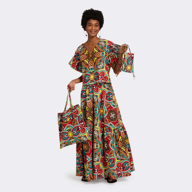 Model wears the Ruffled Top in Wax African Dream with the colors yellow, blue and red and the matching Flounced Maxi Skirt in Wax African Dream with the colors yellow, blue and red. She is holding the Tote Bag with Rouche in Wax African Dream and the Crossbody Mini Bag in Wax African Dream with the same colors for a total look.