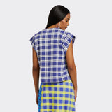 Model wears a V-Neck top with short sleeves. The print is Maasai Check in blue and white. She is also wearing a Maasai Check wrap skirt in blue and yellow.