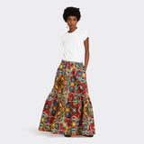 Model wears Flounced Maxi Skirt in Wax African Dream with the colors yellow, blue and red with a plain white tshirt.